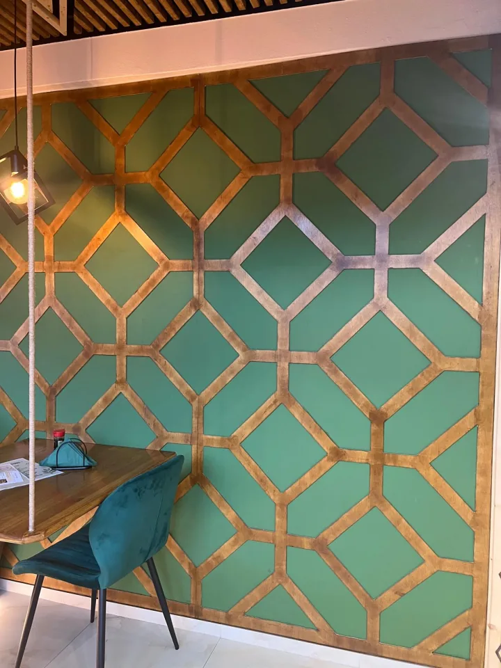 Zăbreaua geometrică de alamă pe peretele verde jade